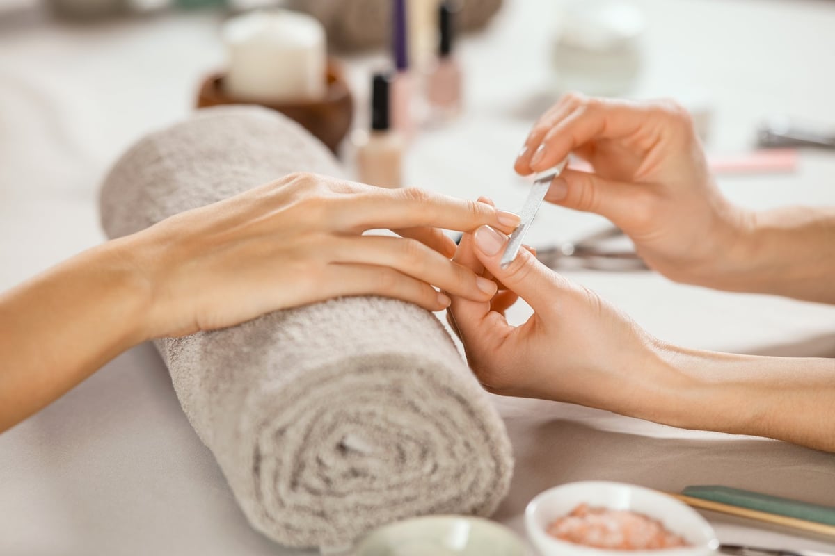 Manicure professionale in salone, estetista che lima le unghie di una cliente